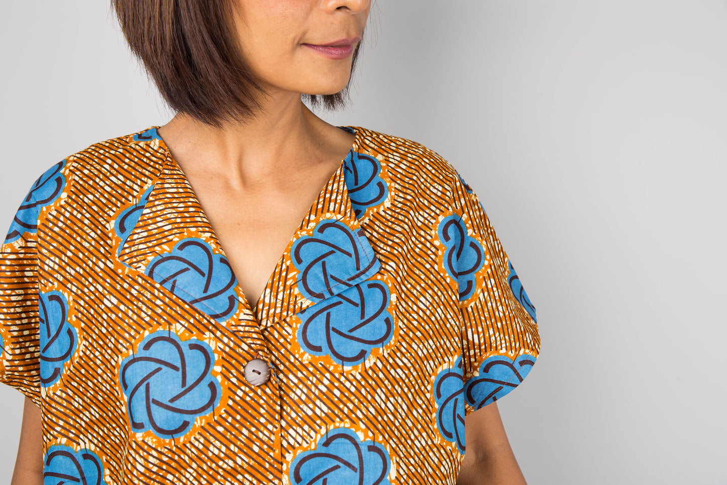 Mid length cotton ankara dress with blue print. Close up view of a dress with cap sleeves and african print
