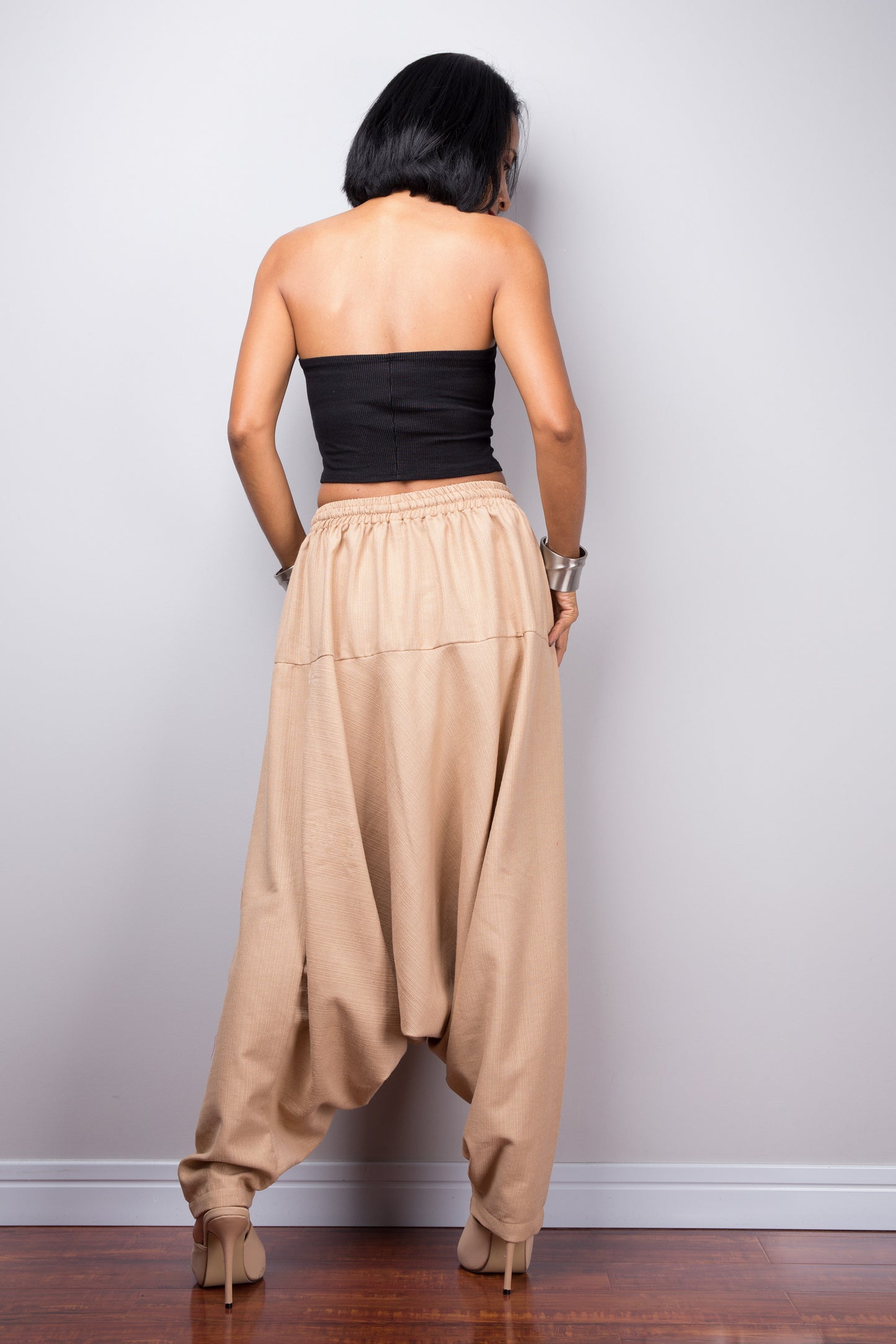 Back view of the model in beige harem pants, showing how the pants drape and the fit around the hips.