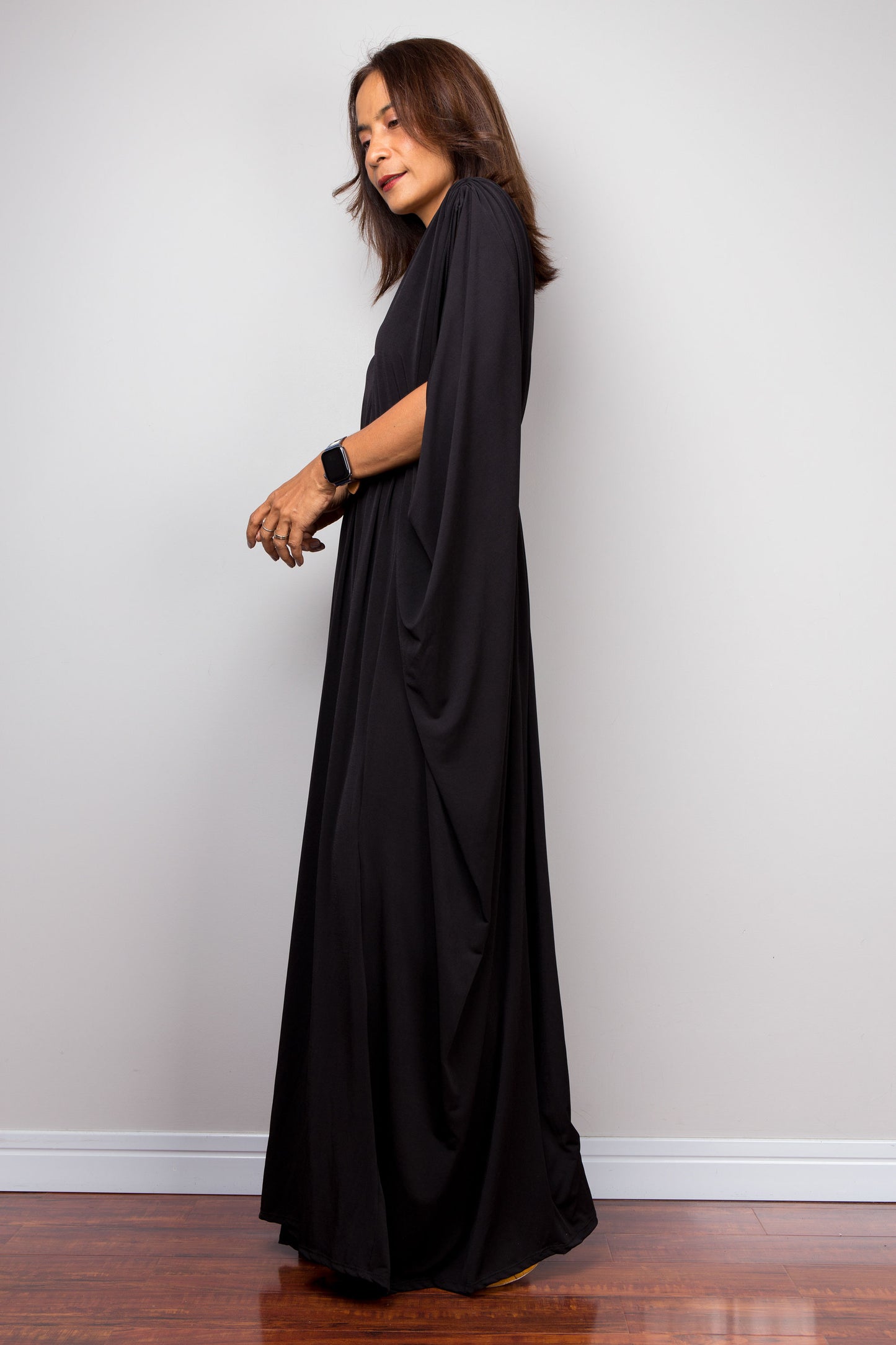 Long black kaftan dress with v neck and braided detail on the waist. Side view