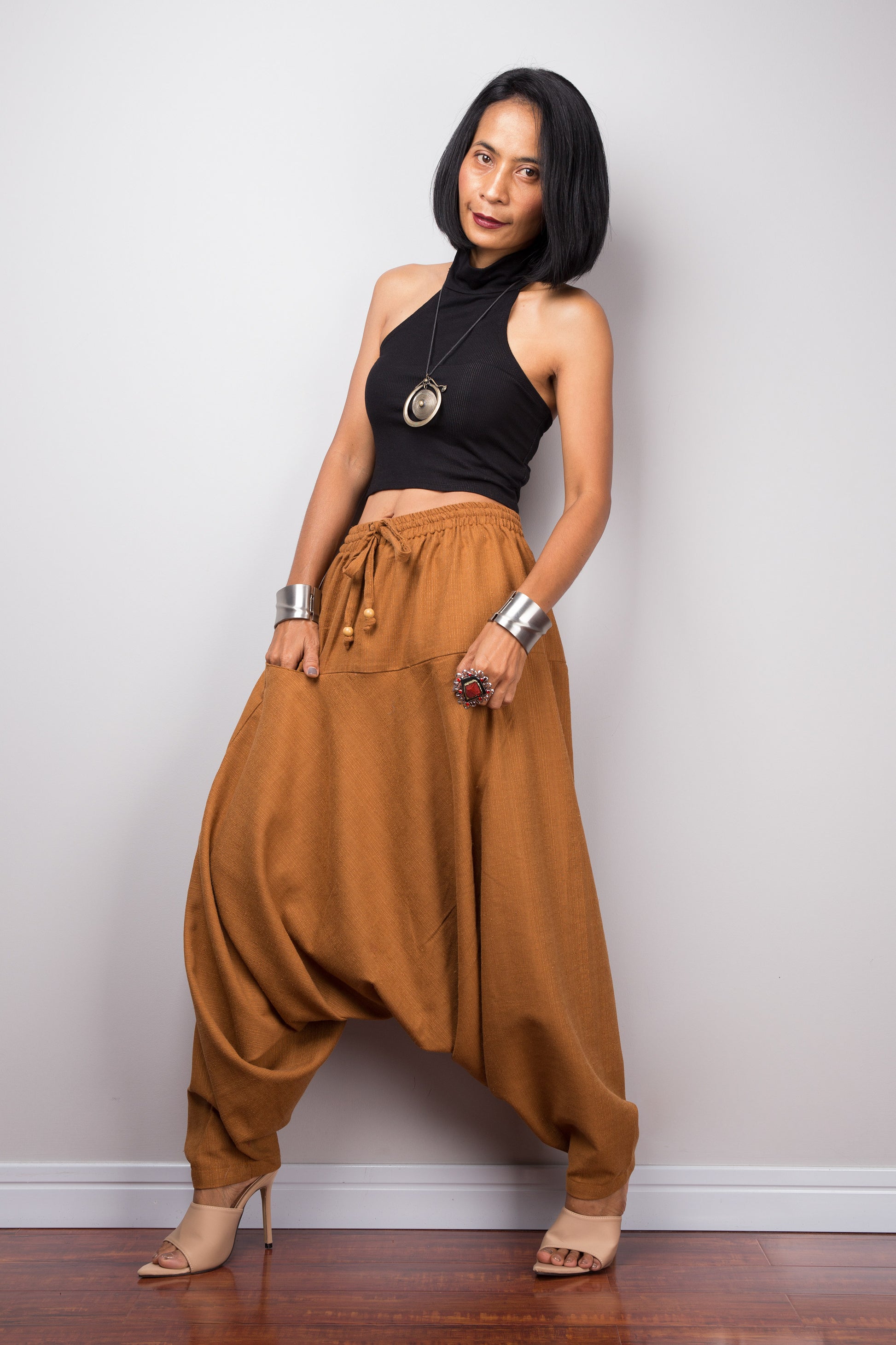 Side view of the brown harem pants, displaying the loose fit and the flow of the fabric from the waist to the hem.