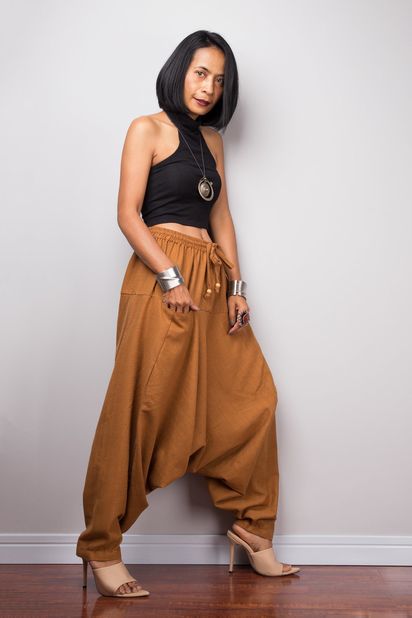 Side view of the brown cotton harem pants, displaying the loose fit and the flow of the fabric from the waist to the hem.