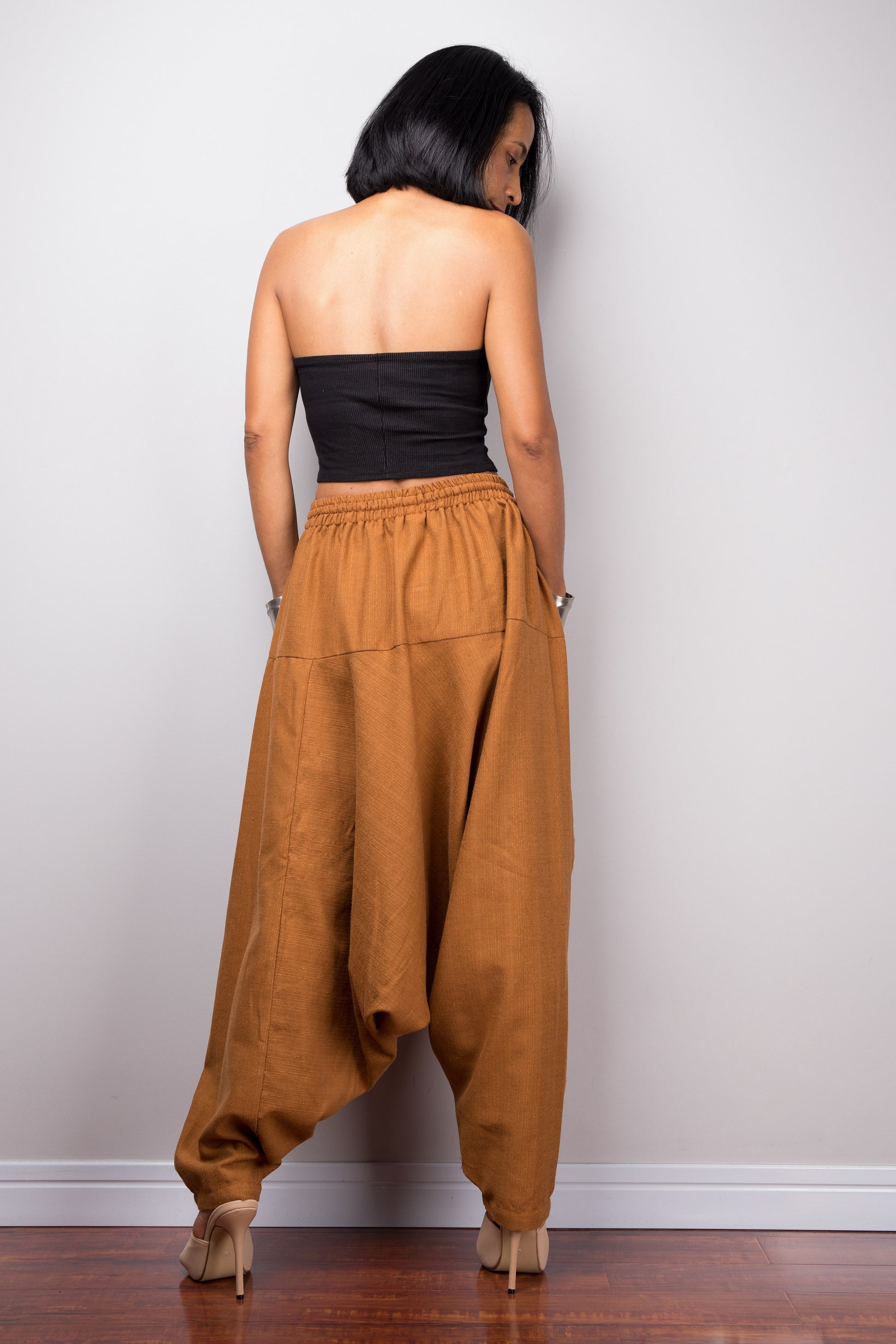 Back view of the model in brown harem pants, showing how the pants drape and the fit around the hips.