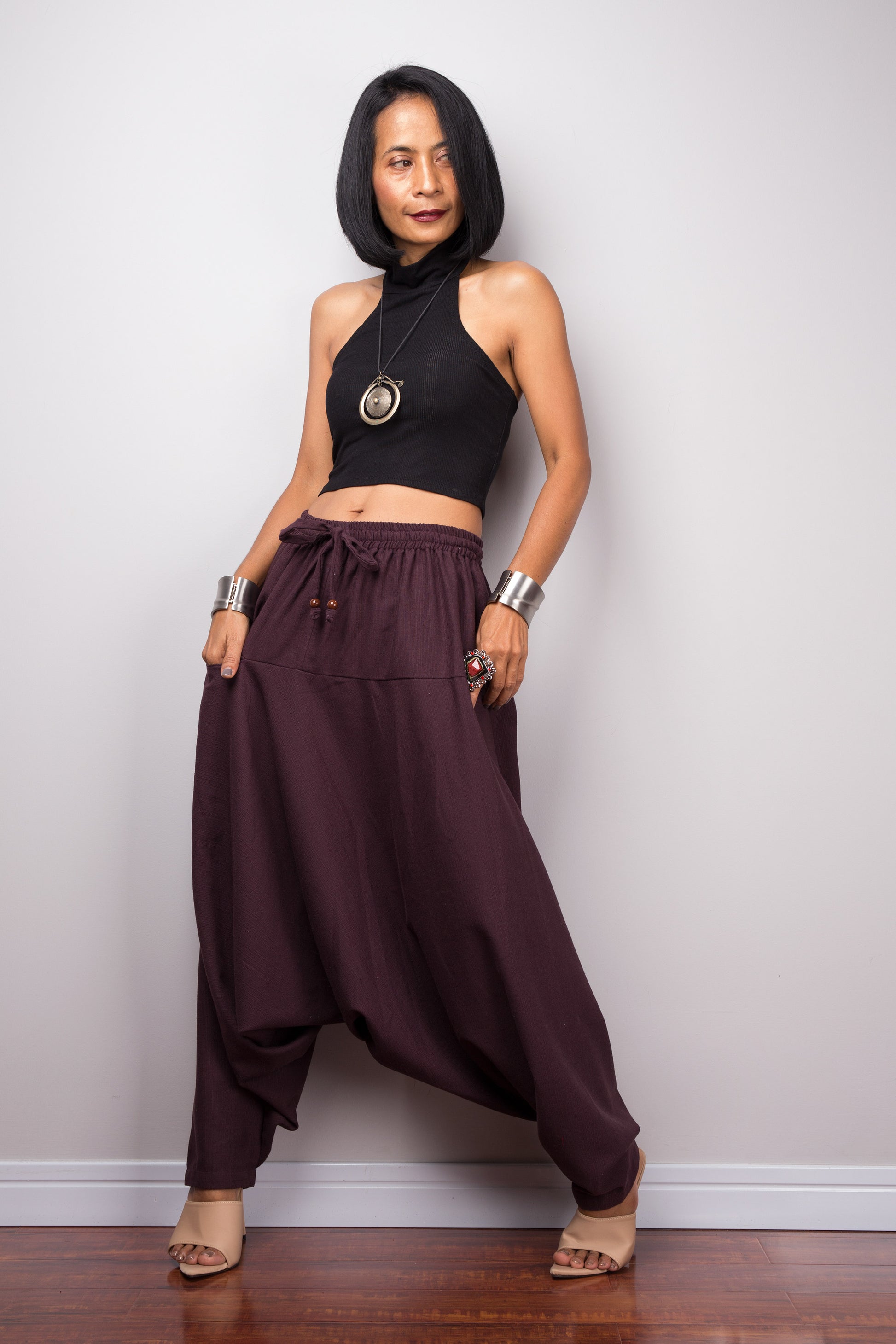 Model wearing burgundy harem pants with a loose fit, standing against a plain background, showcasing the full-length view.