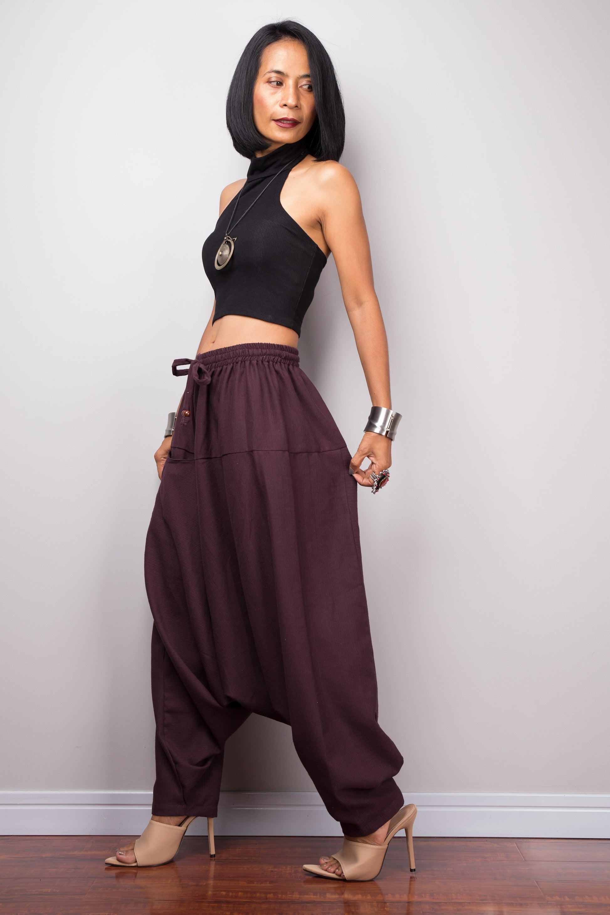 Side view of the burgundy harem pants, displaying the loose fit and the flow of the fabric from the waist to the hem.