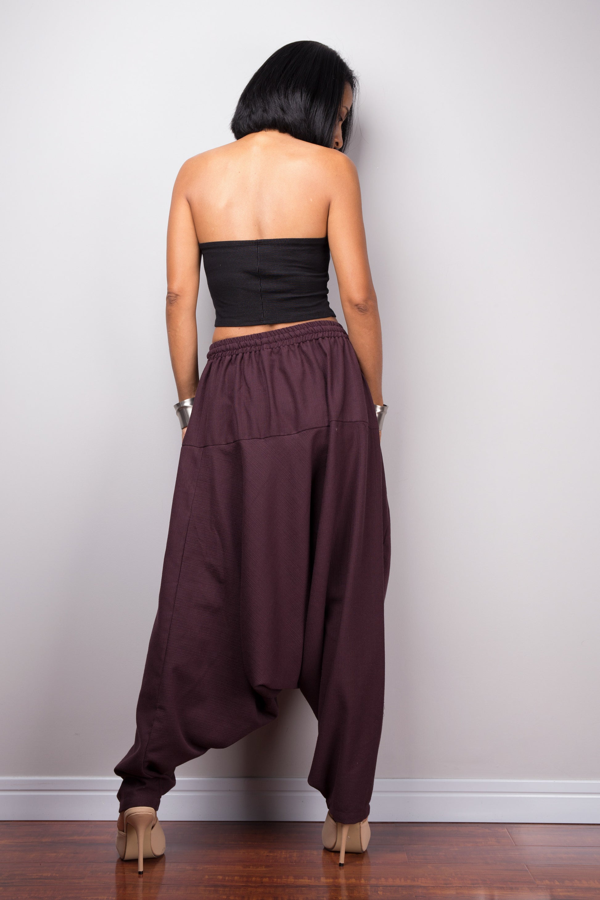 Back view of the model in burgundy harem pants, showing how the pants drape and the fit around the hips.