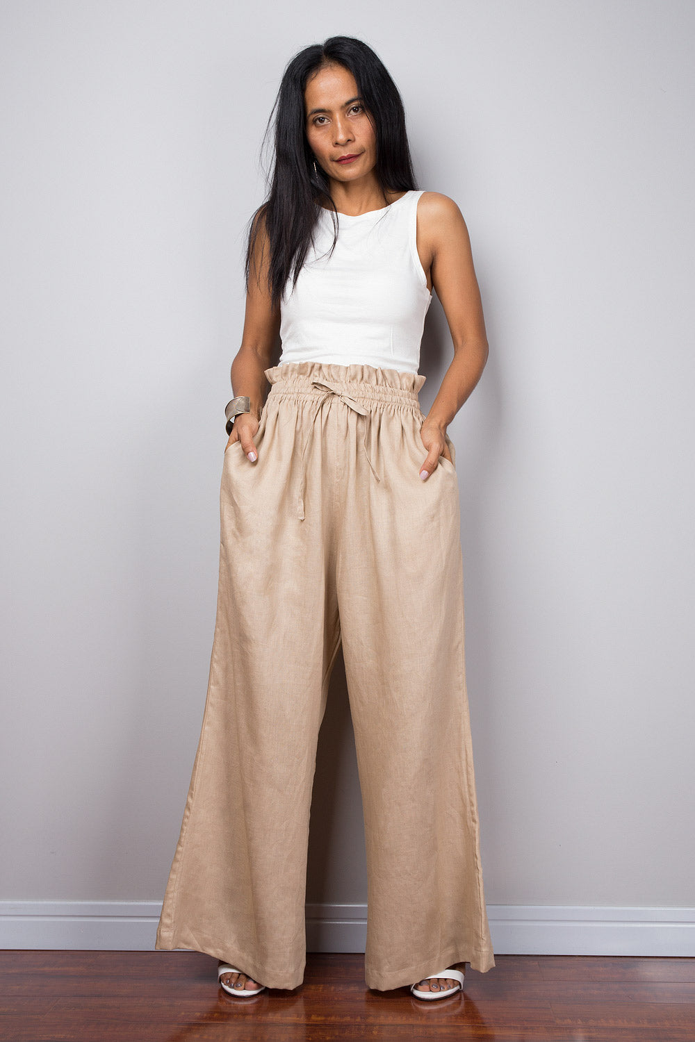 Woman standing in beige handmade linen palazzo pants, demonstrating the length and flow of the wide leg design.