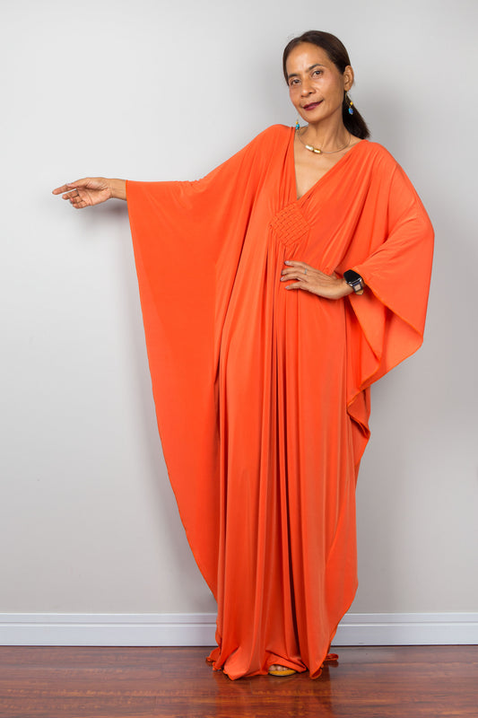 Orange kaftan dress with batwing sleeves and plunging v neckline. Braided diamond detail on the chest. Design by Nuichan