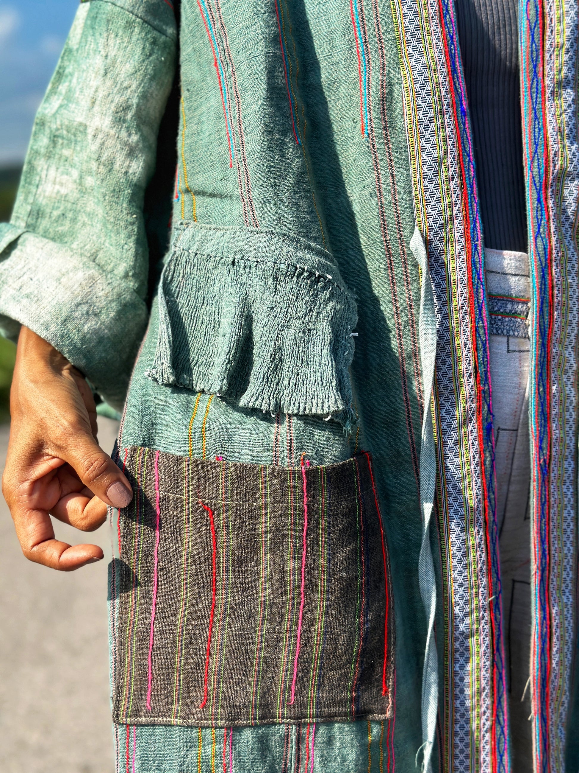 Patchwork coat with embroidered pocket.  Close up view 