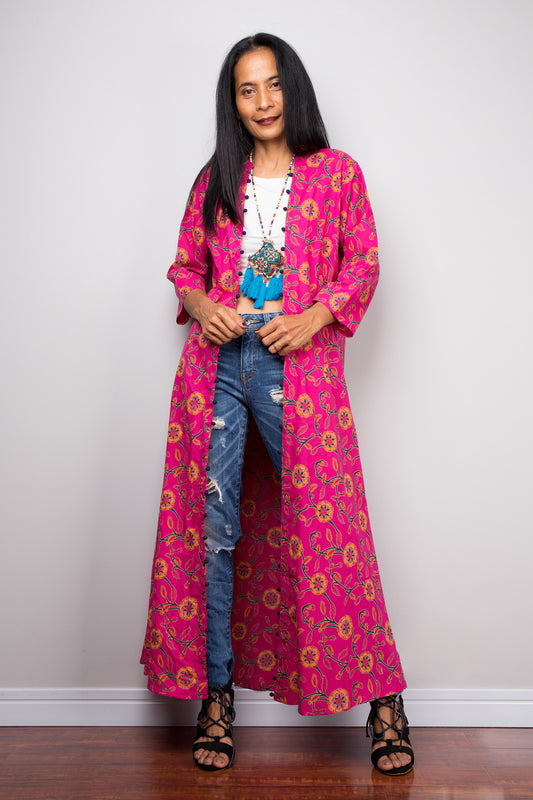 Woman wearing a vibrant pink floral cotton open front cardigan over a white top and ripped jeans, showcasing the kimono style.