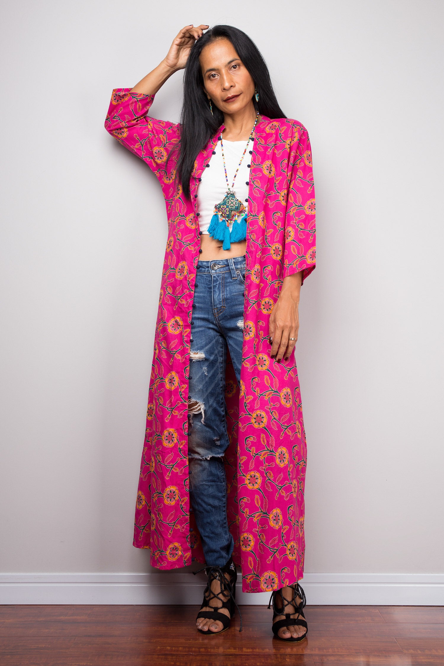 Close-up of a woman in a pink floral cotton cardigan, highlighting the open front design and hand placement on jeans.