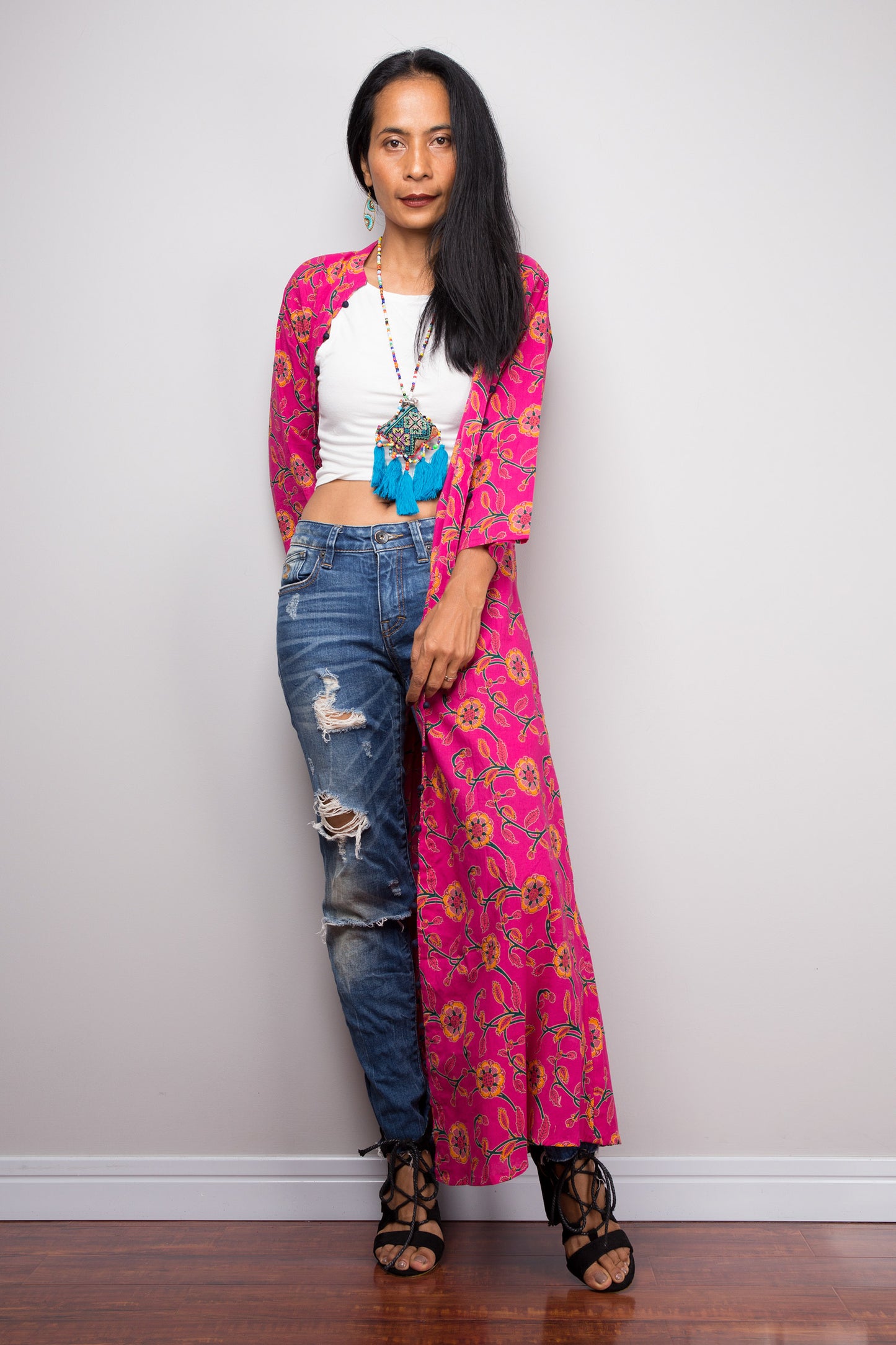 Profile view of the pink floral cotton cardigan, emphasizing the side slit and the contrast with blue jeans.