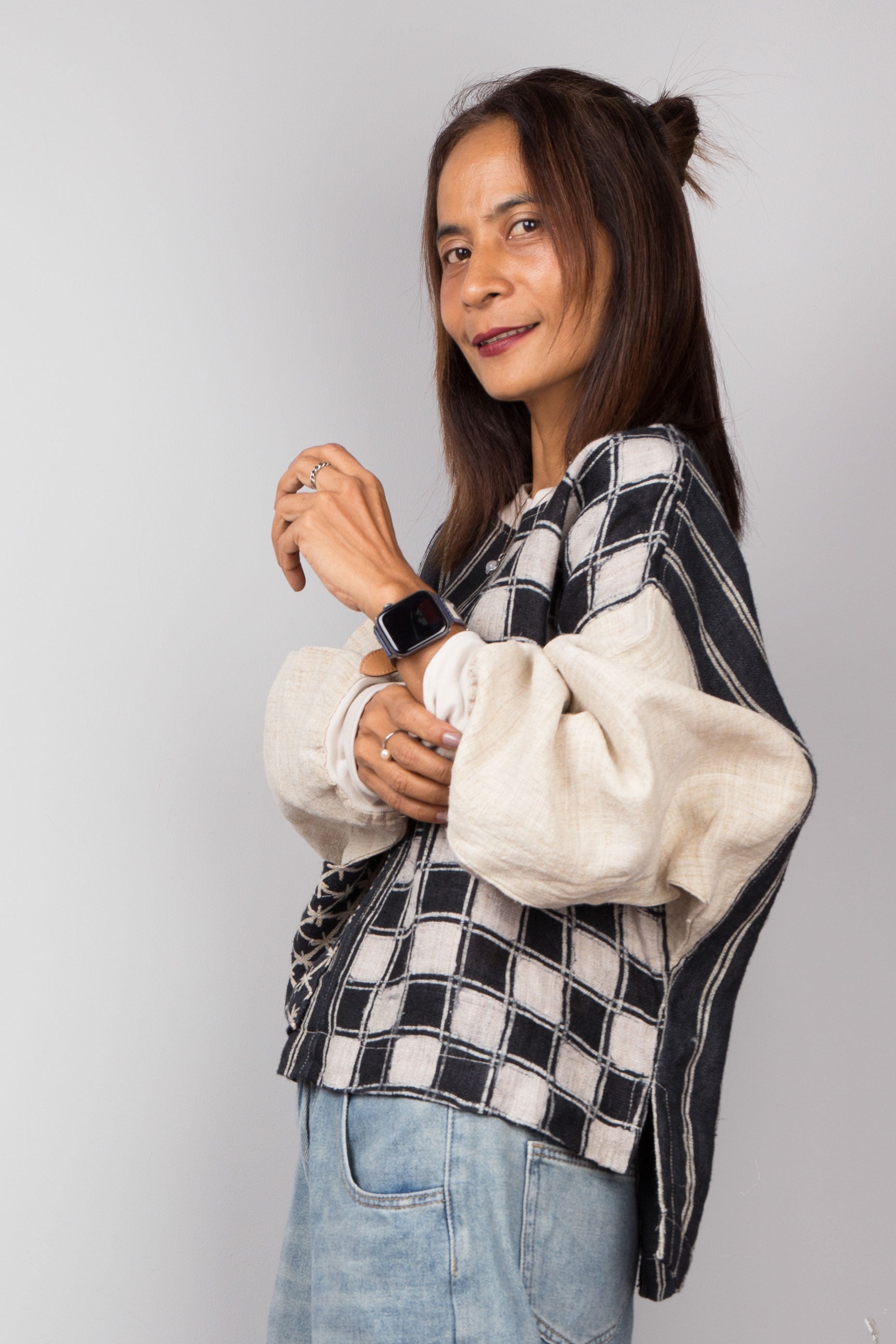 Handwoven hemp sweater with combination of a checkered and striped pattern. Two tone in black and off white. Model is rolling up the sleeve. Long sleeve pullover top with crew neck