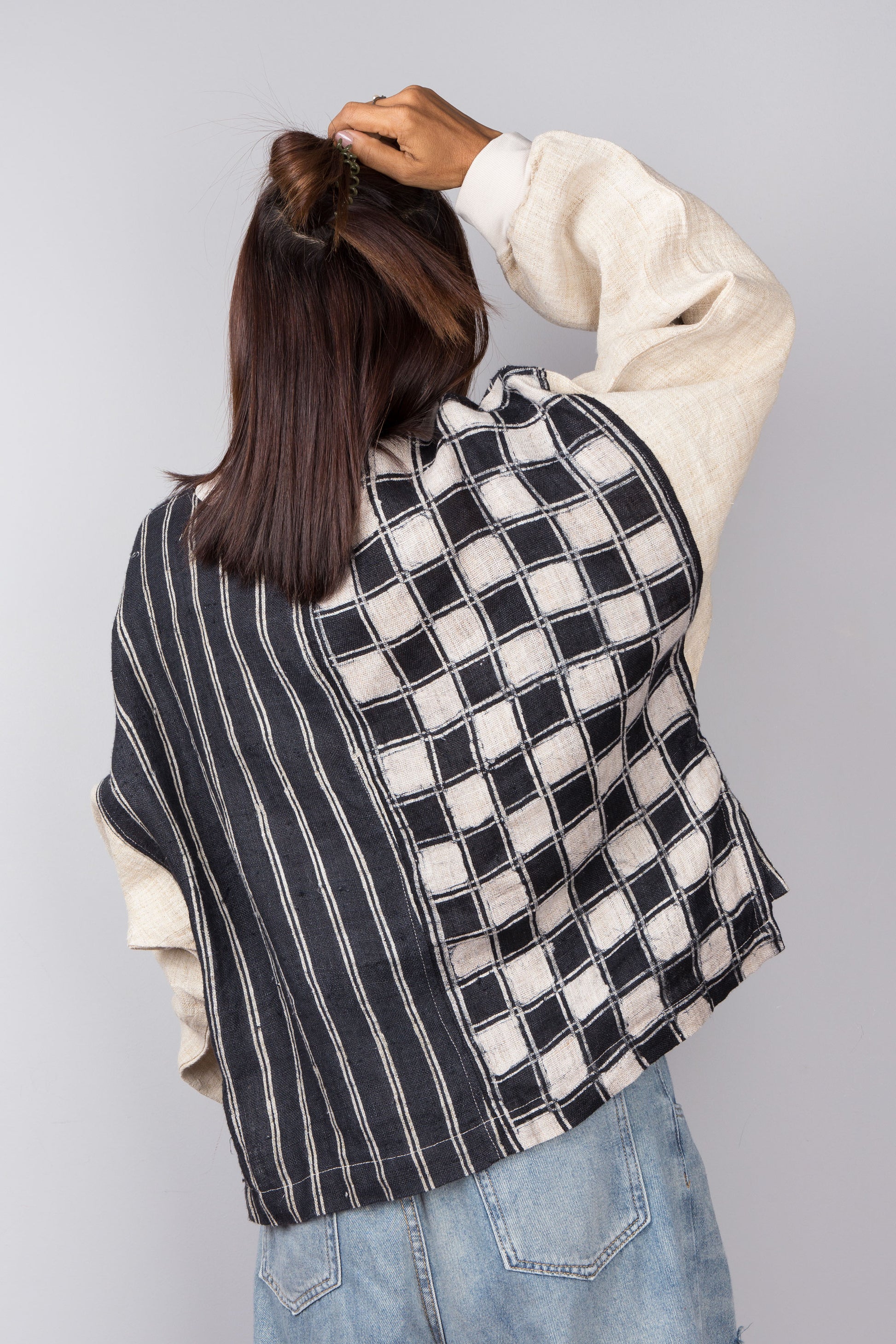 Handwoven hemp sweater with combination of a checkered and striped pattern. Two tone in black and off white. Back view. Long sleeve pullover top with crew neck