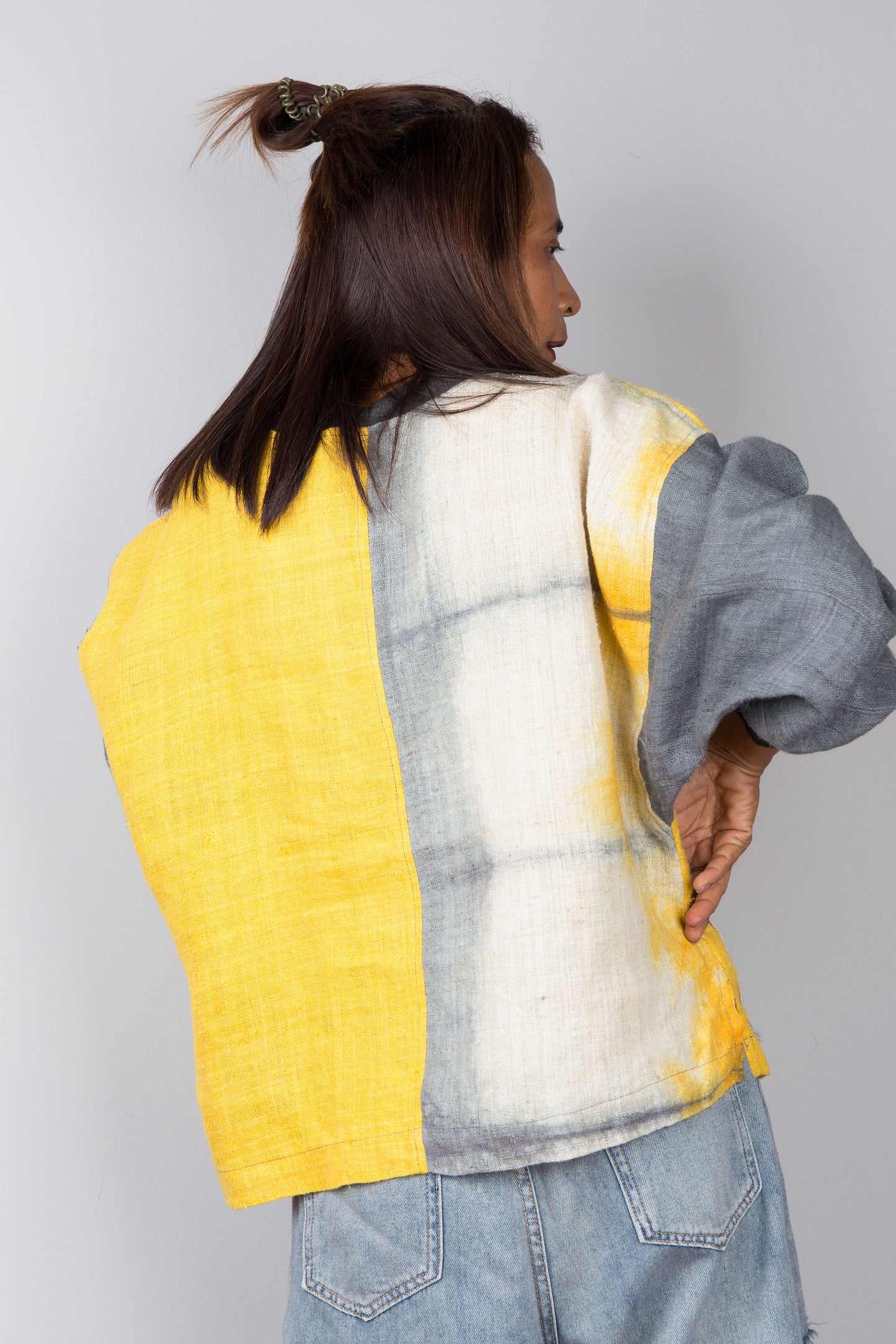 Hemp sweater in yellow and grey with shibori tie dye detail on the front pocket. Back view.