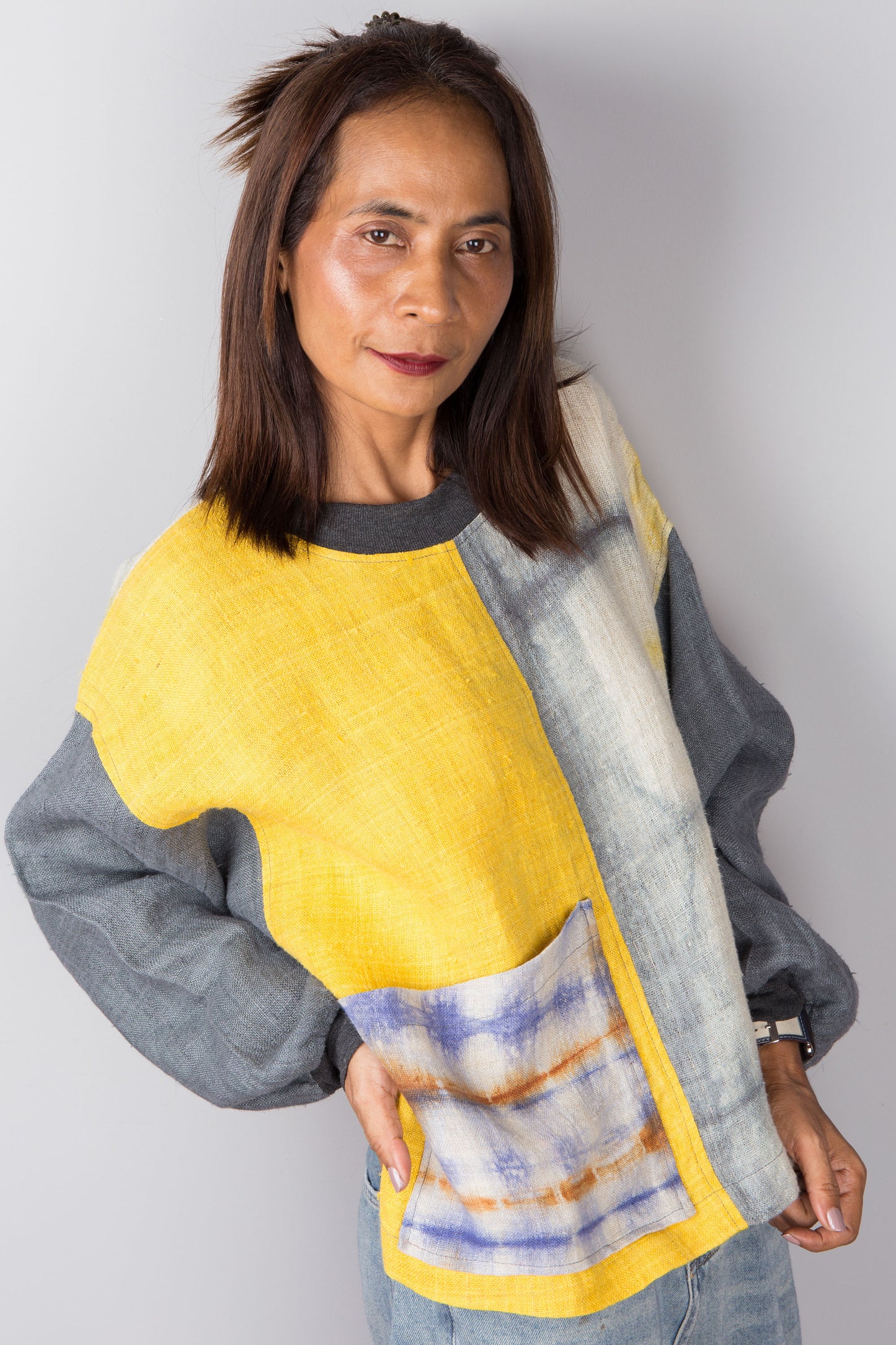 Hemp sweater in yellow and grey with shibori tie dye detail on the front pocket -  close up view