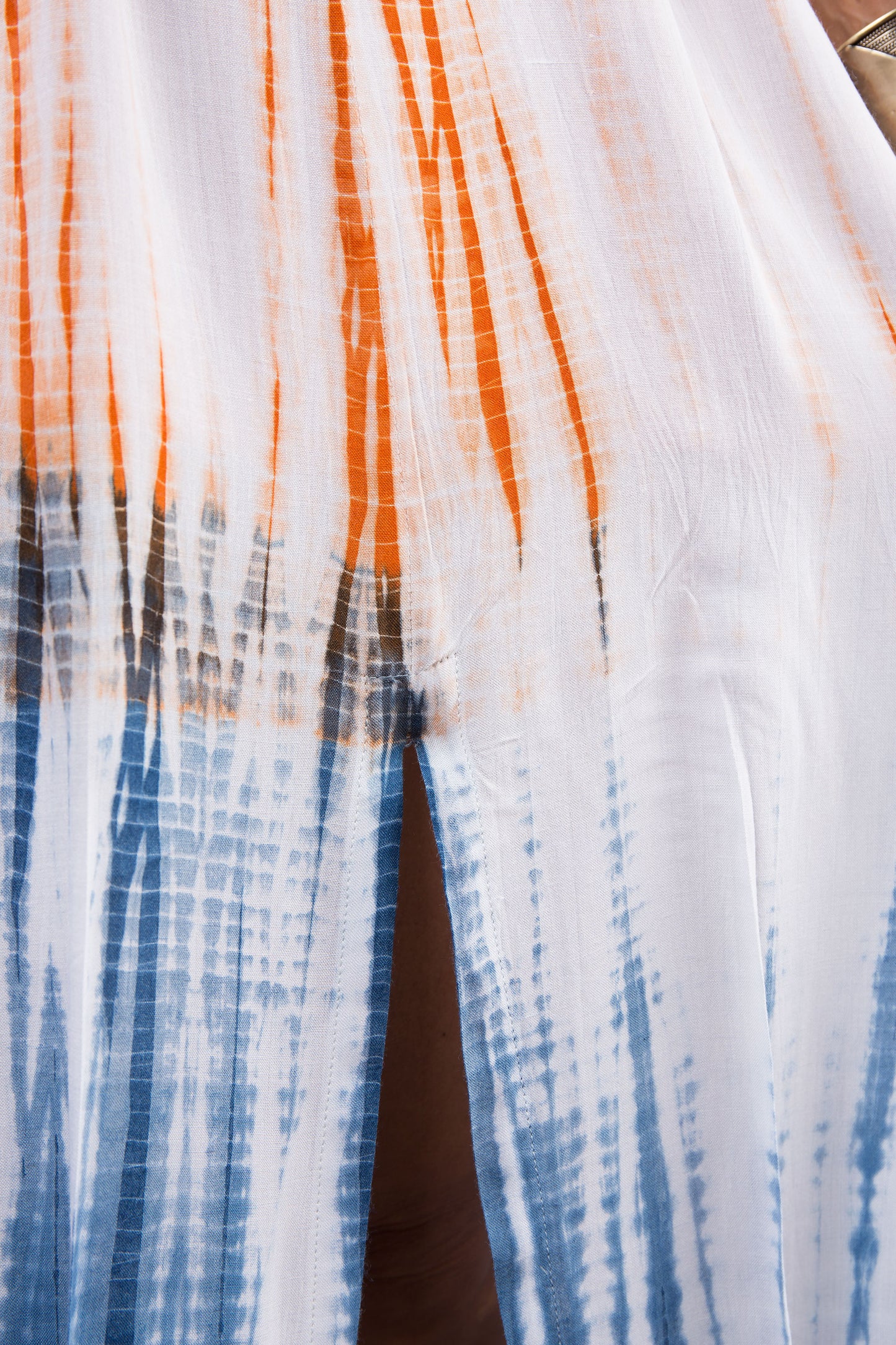 Close-up of the intricate shibori tie dye pattern on the blue and orange cotton dress, highlighting the unique design.