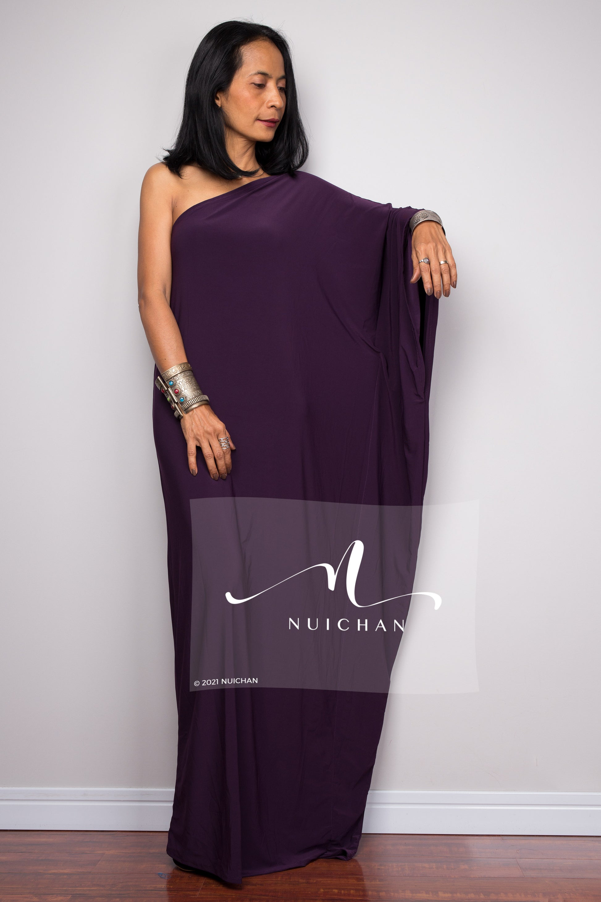 Flowing purple one-shoulder evening dress with intricate details, perfect for formal events.