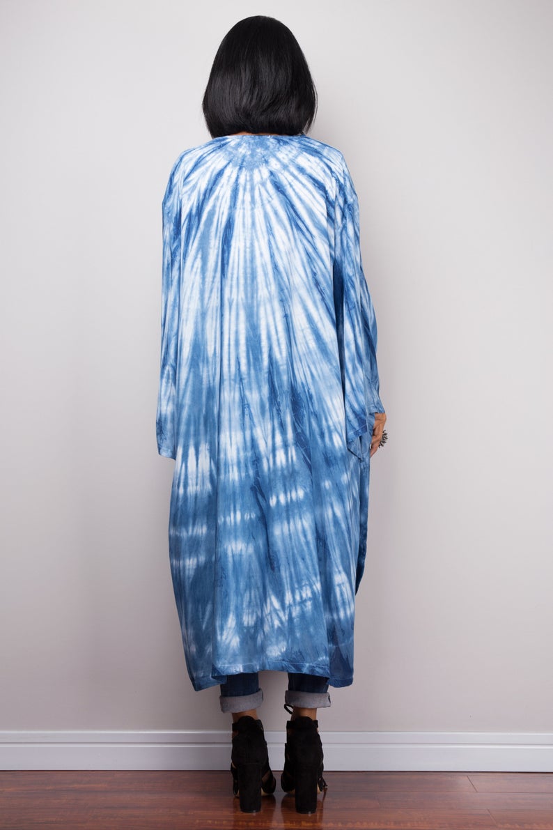 Woman wearing natural indigo shibori tie-dye open front cardigan with pockets. Back view