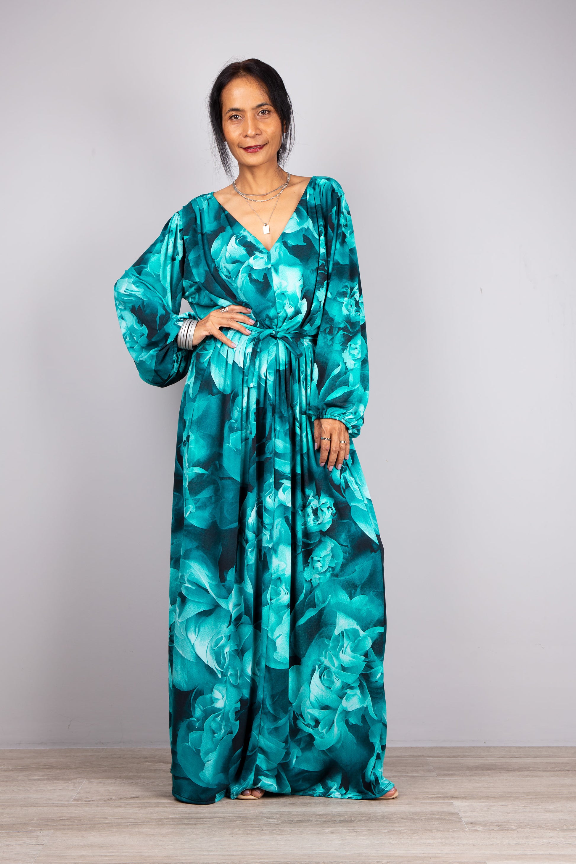 Elegance Meets Boho: Here's our model in the quintessential boho piece - a turquoise maxi dress that stands out beautifully against the light grey scenery.