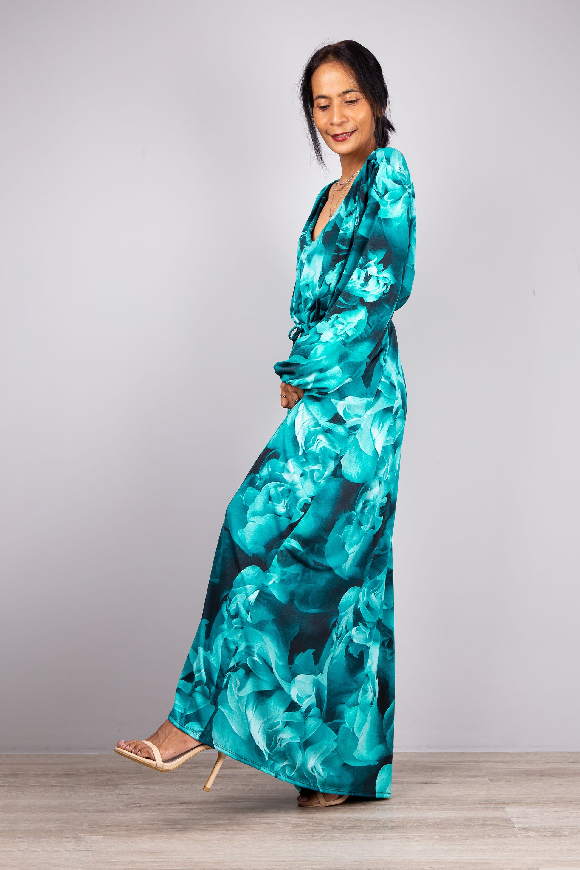 Serene Boho Style: The model stands in our Long Sleeve Maxi Dress, its vibrant turquoise shade popping against the light grey, inviting you into a world of boho elegance.